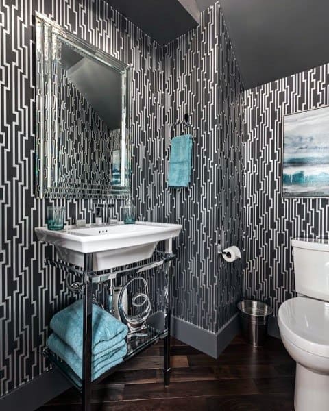 Bathroom with black and white geometric wallpaper, pedestal sink, and teal accents.