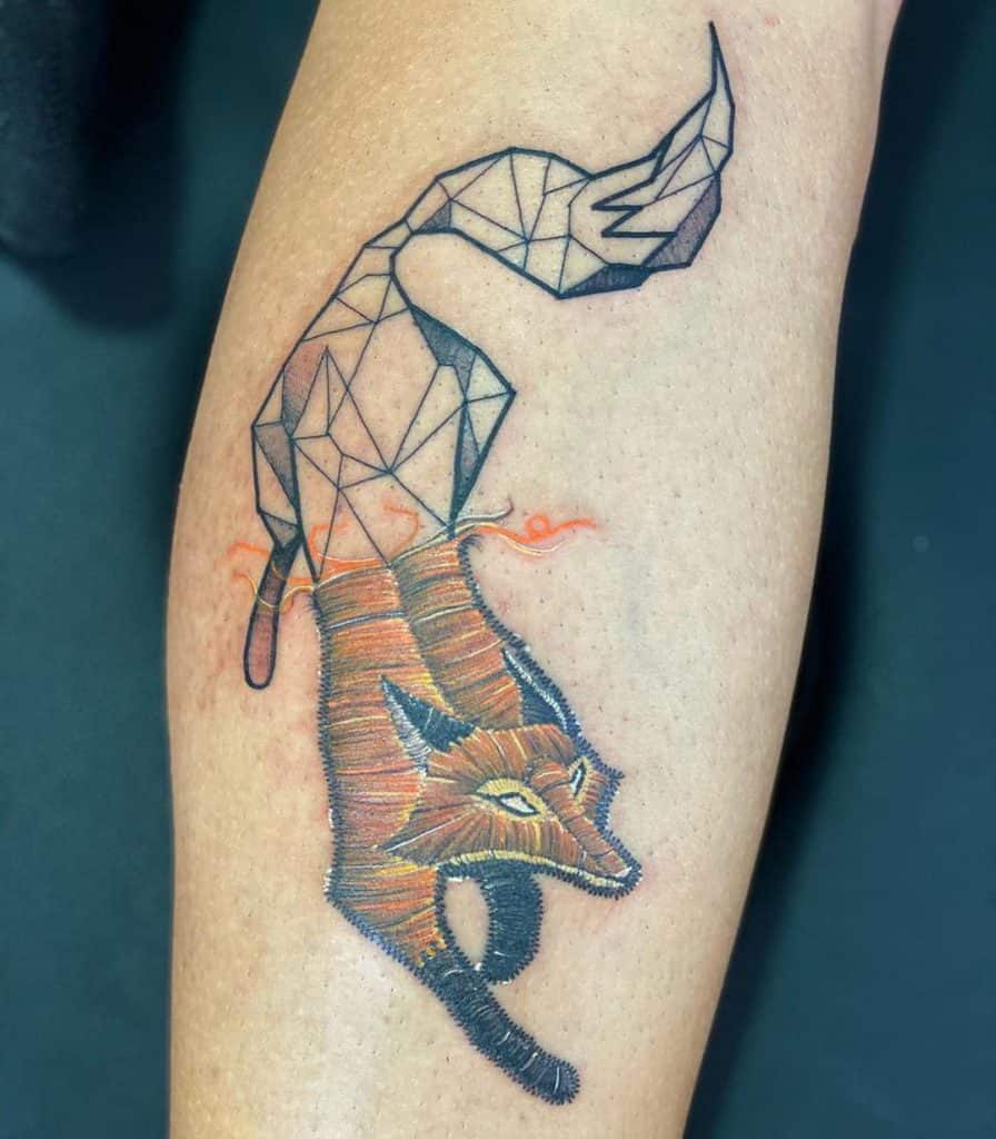 Artistic fox tattoo featuring a textile embroidery texture on the head and body, fading into a polygonal tail.