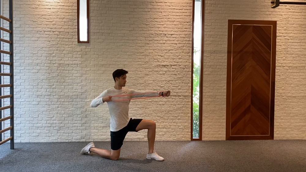 young man doing half kneeling archer pull shoulder exercise indoor
