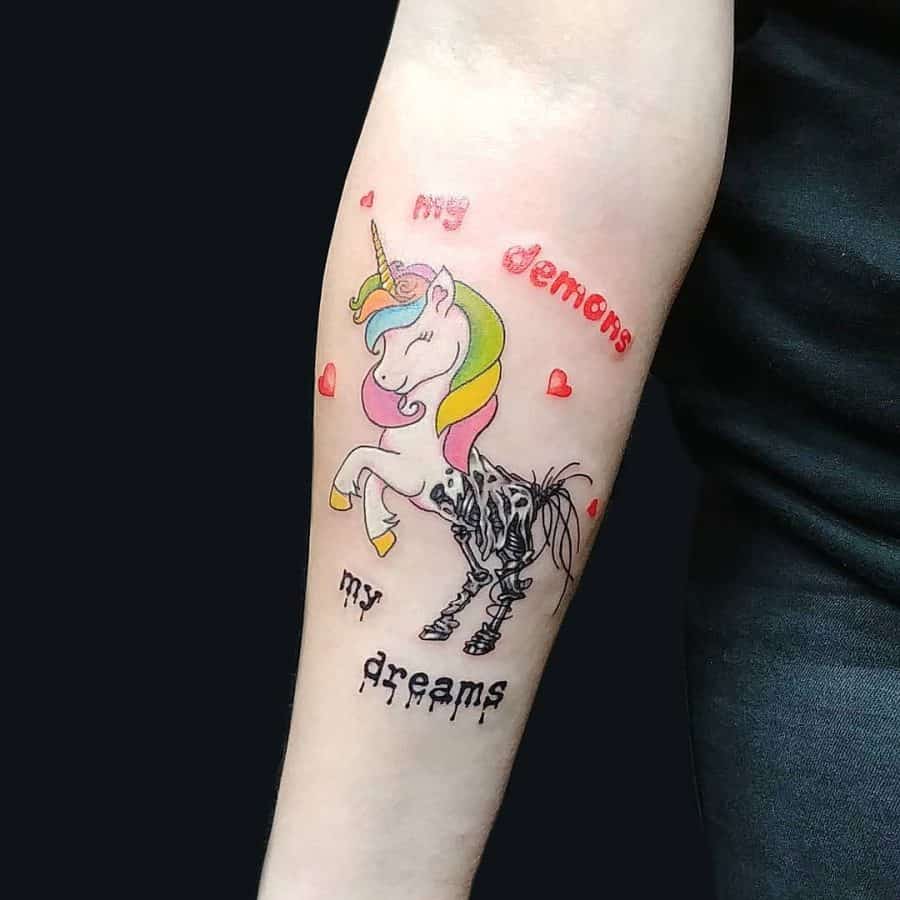 Colorful unicorn tattoo with a skeletal hind leg, symbolizing 'my dreams' vs. 'my demons' in contrasting fonts and heart accents.