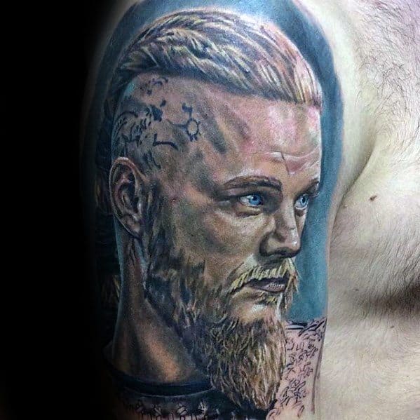 Tattoo of a man with a braided mohawk, beard, and stern expression on a shoulder