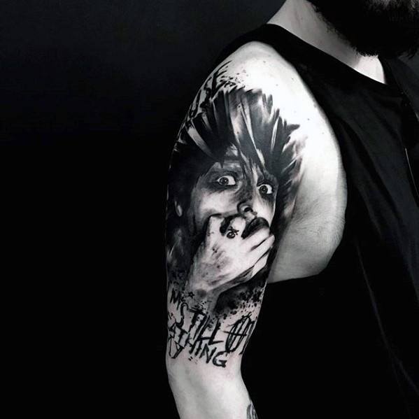 Black and grey tattoo of a distressed face with wild hair and a hand over the mouth, featuring “No Still Breathing” text in grunge style.