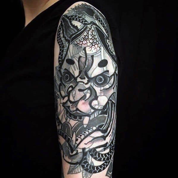 Blast-over tattoo showcasing a fierce and intricate oni mask design, blending traditional Japanese elements with bold shading and patterns on the upper arm