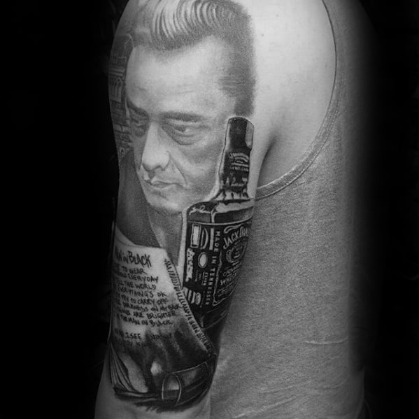 Johnny Cash tattoo beside a Jack Daniel's bottle on a person's upper arm