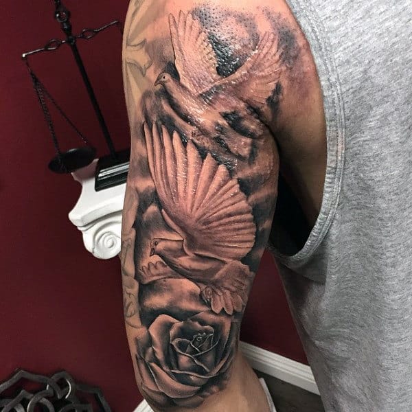 Tattooed arm with doves in flight, a rose, and a scale against a red wall background