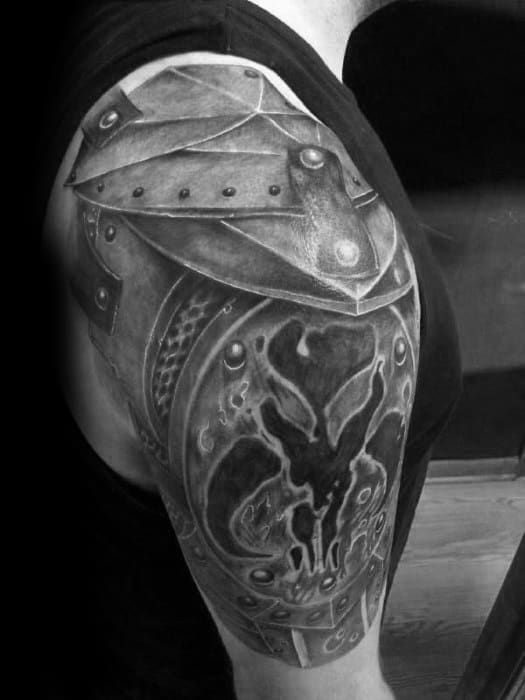 Intricate Mandalorian armor tattoo with Mythosaur skull emblem, designed to mimic a shoulder pauldron in detailed black and gray shading.