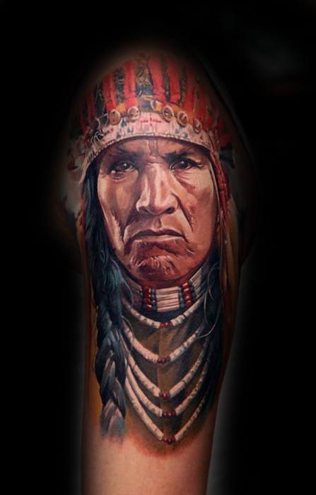 Tattoo of a Native American chief with a feathered headdress and braided hair on a dark background