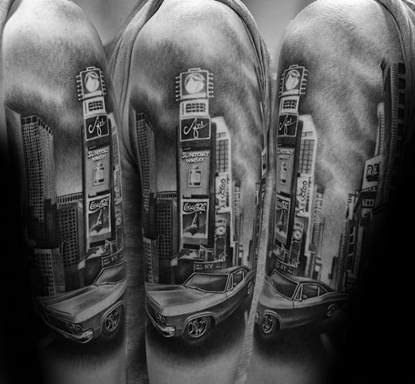 Realistic black and gray upper arm tattoo of Times Square with vintage billboards and a classic car in the foreground.