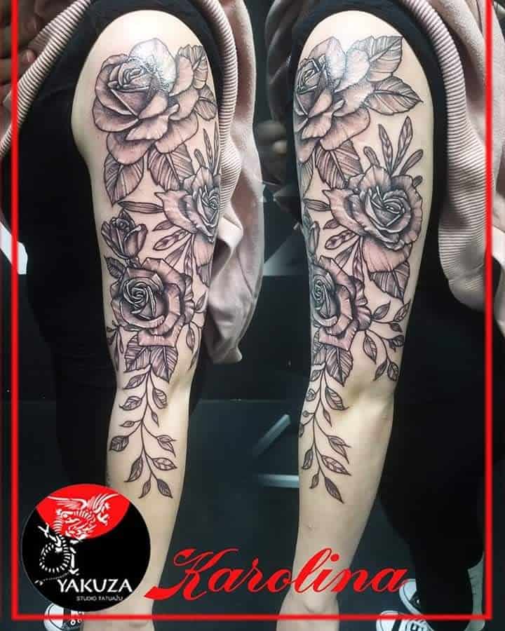 Black and gray rose tattoo on upper arm with leaves
