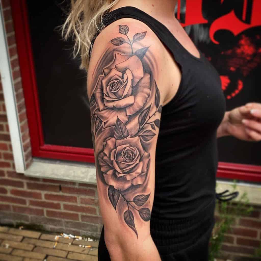 Woman with a detailed black rose half-sleeve tattoo on her upper arm
