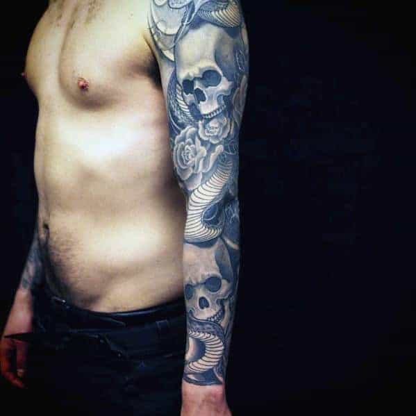 Man with a sleeve tattoo featuring skulls and roses on his right arm