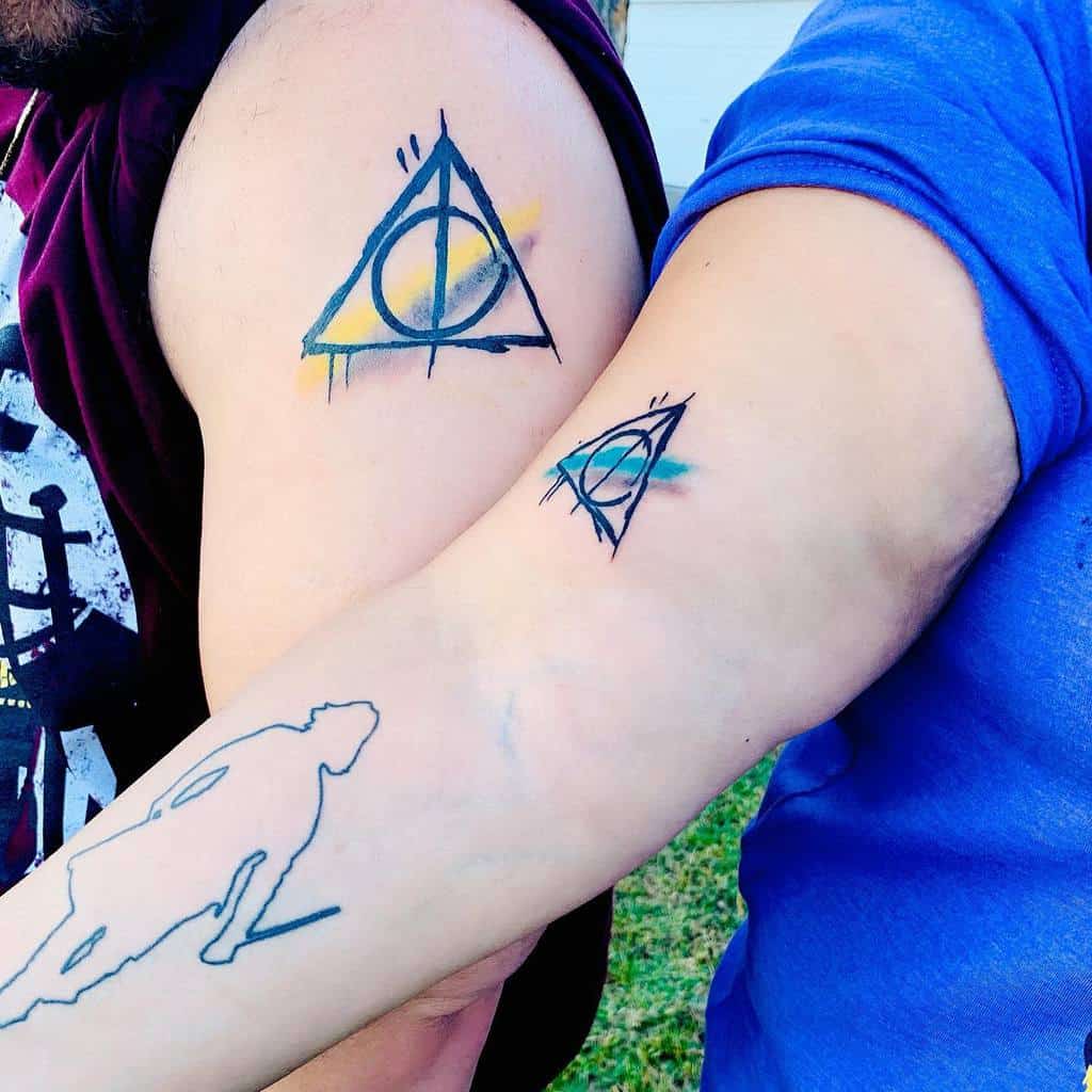 Matching Deathly Hallows tattoos with watercolor accents in yellow and blue