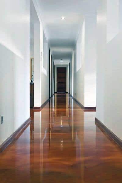 A long hallway with polished concrete floors and white walls, leading to a closed door at the end