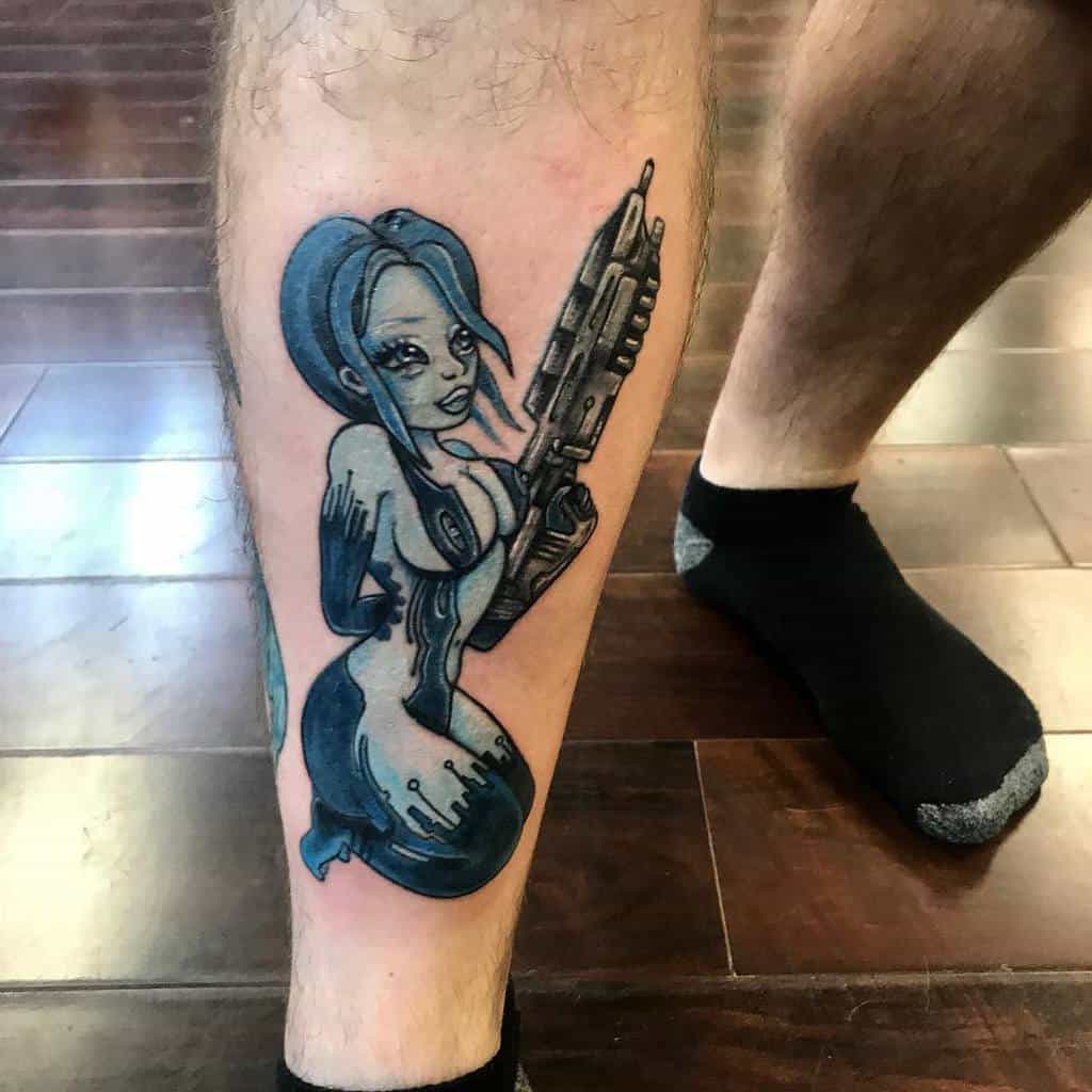 Cartoon-style tattoo of Cortana from Halo, featuring a blue digital aesthetic, holding a futuristic weapon, inked on the lower leg.