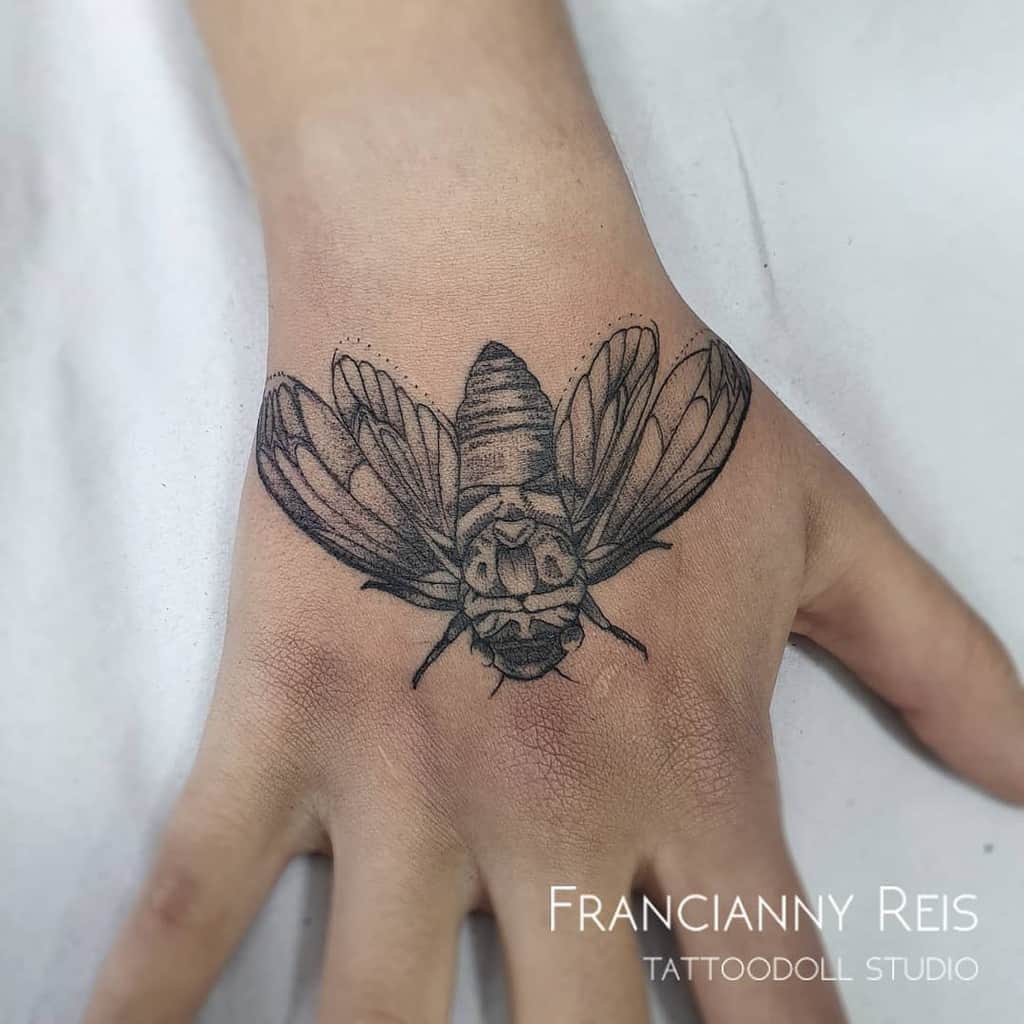 Minimalist cicada tattoo on the hand with fine linework and shading, showcasing delicate wing and body details