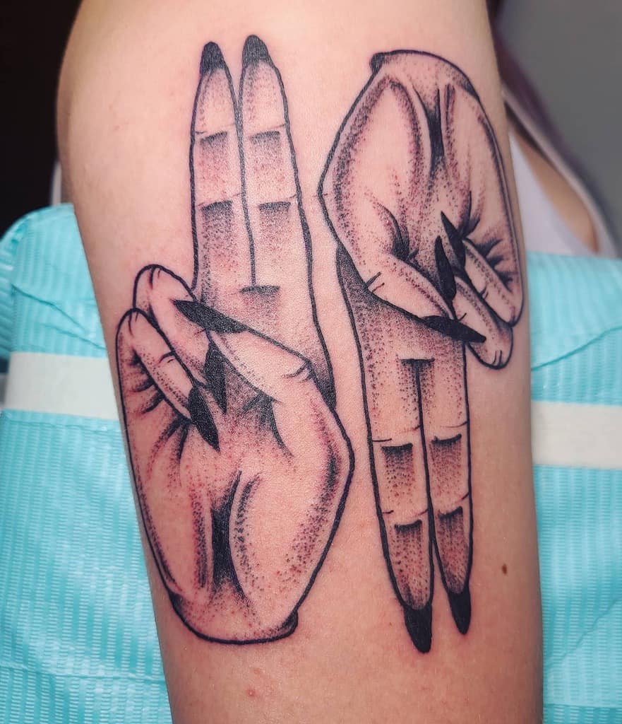 Bold upper arm tattoo of hands depicting 'as above, so below,' featuring dotwork shading and elongated nails for dramatic effect