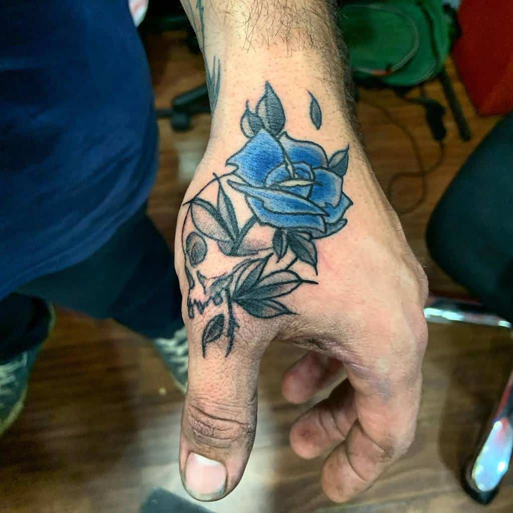 A stunning hand tattoo featuring an intricately detailed blue rose, with delicate leaves elegantly trailing across the skin
