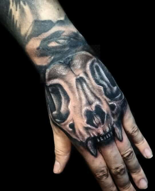 Hand tattoo of a realistic, fierce cat skull with prominent teeth