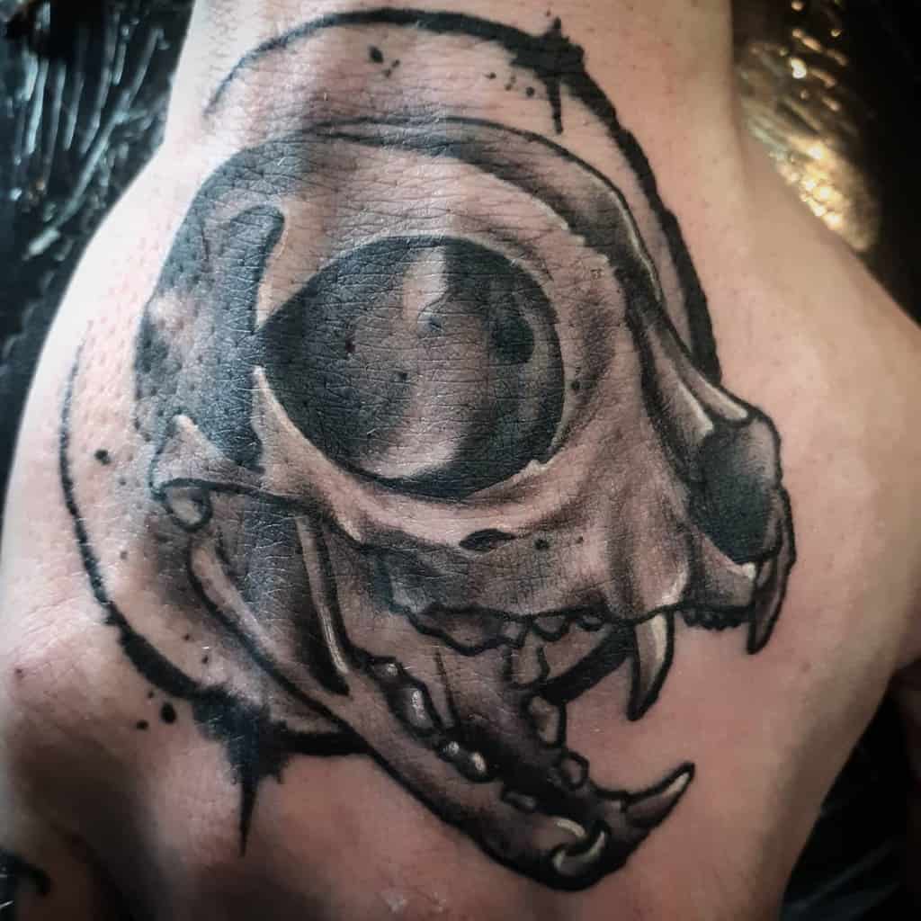 Hand tattoo of a detailed cat skull with large eye sockets and prominent teeth
