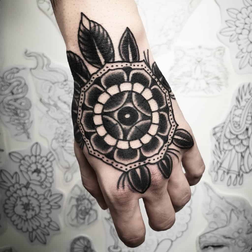 Black and white mandala tattoo on the back of a hand