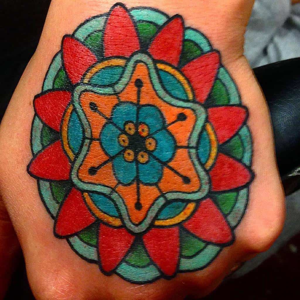 Colorful geometric flower tattoo with red, blue, and green patterns on a hand