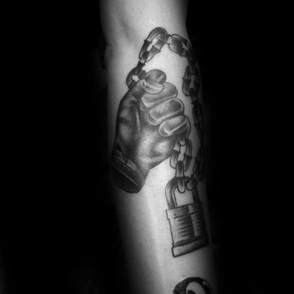 Hand Holding Chain With Padlock Tattoo On Males Forearm