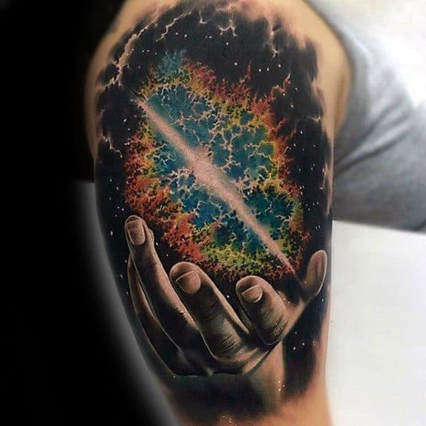 Tattoo of a hand cradling a cosmic sphere, surrounded by colorful nebula and stars on a person's arm
