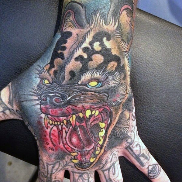 Hyper-detailed hyena tattoo on the hand with glowing yellow eyes, exposed gums, sharp fangs, and vivid red tones for an intense, aggressive look.