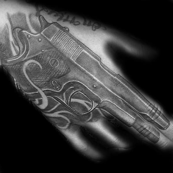 Realistic black and gray tattoo of a 1911 pistol on the hand, designed with fine details and shading to create a bold three-dimensional effect.
