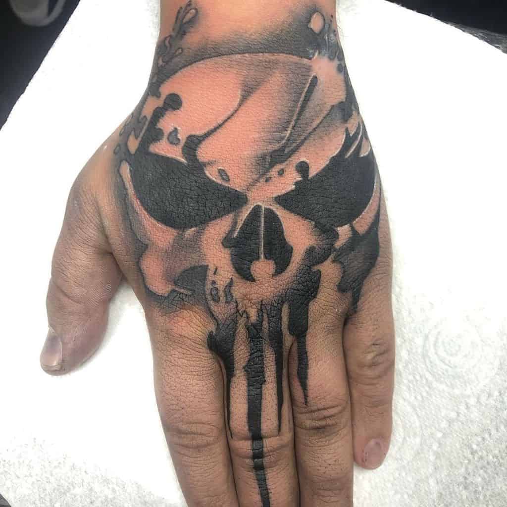 Punisher Skull tattoo on the hand, featuring bold black ink with splatter-like details for a rough, dynamic, and edgy appearance
