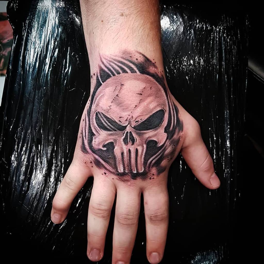 Punisher Skull tattoo on the hand, rendered in a realistic style with detailed shading and pink undertones to add a vivid, haunting effect