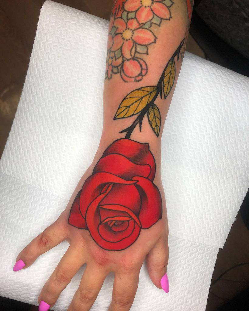 A vibrant red rose among the floral tattoos graces an arm