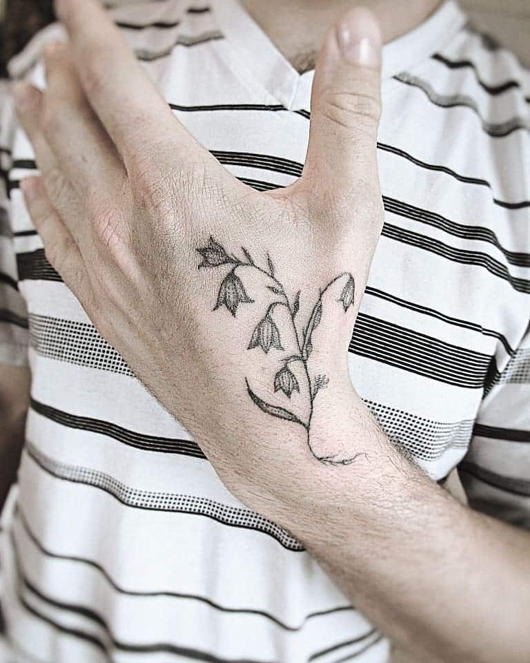 Delicate black ink Lily of the Valley tattoo, featuring fine lines and subtle shading for a minimalist, elegant look