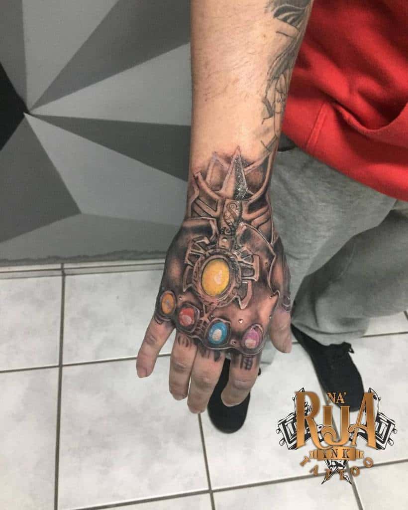 A detailed black and gray tattoo of the Infinity Gauntlet, showcasing all six Infinity Stones and the intricate design of the gauntlet