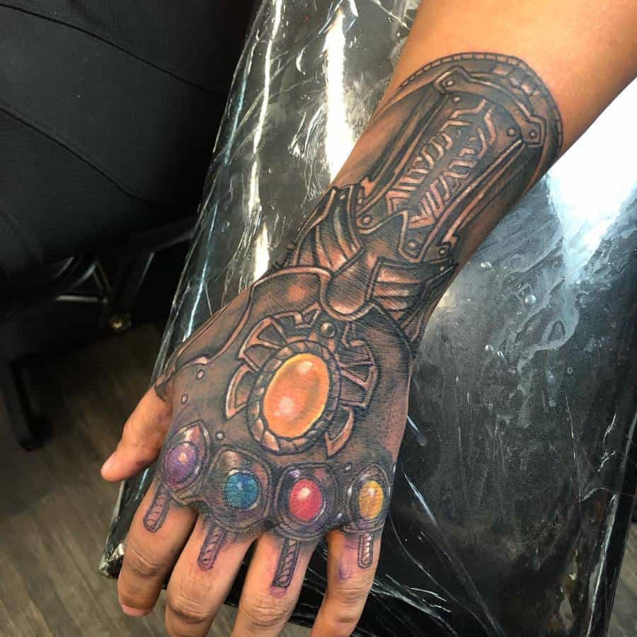 A detailed black and gray tattoo of the Infinity Gauntlet, showcasing the intricate design of the gauntlet and the vibrant Infinity Stones