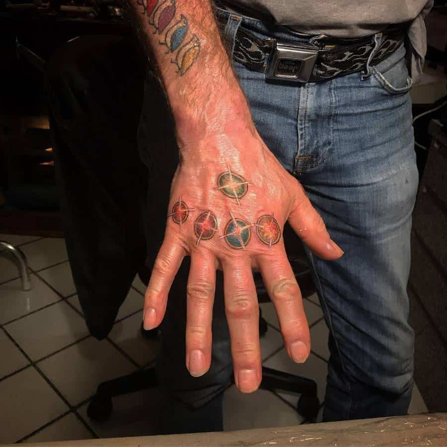 A colorful tattoo of the six Infinity Stones, with each stone placed on different fingers, accompanied by intricate designs around each gem