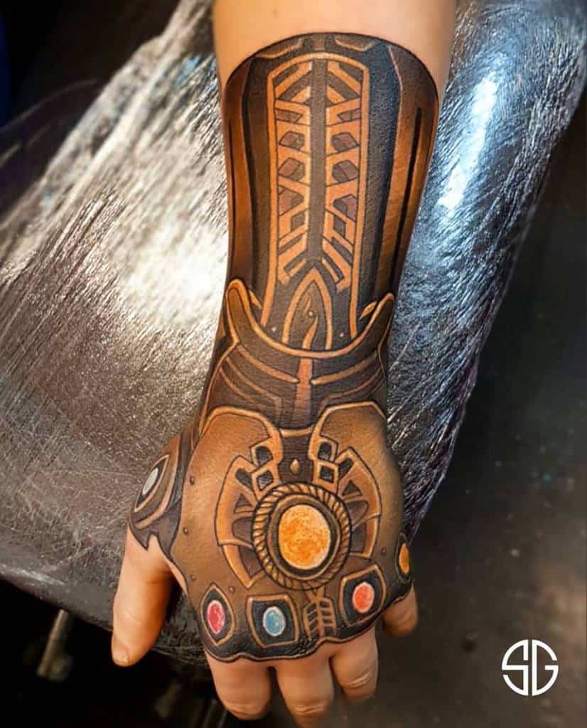 A bold black and orange tattoo of the Infinity Gauntlet, with intricate shading and vibrant colors for the Infinity Stones