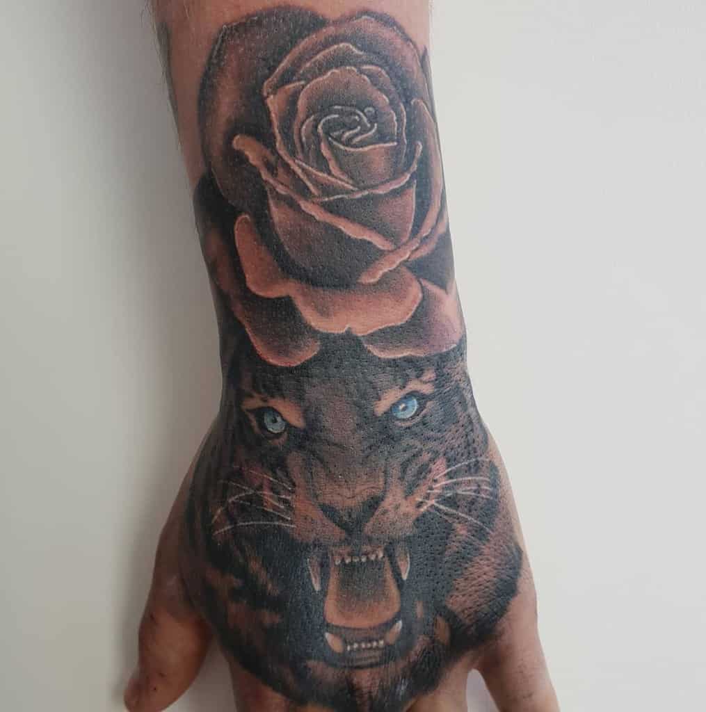 A hand tattoo featuring a roaring tiger and a rose on the top of the wrist