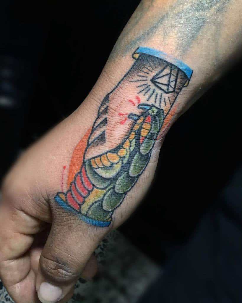 Colorful hand tattoo of a handshake between a human and a snake, featuring a diamond symbol on the wrist and bold shading