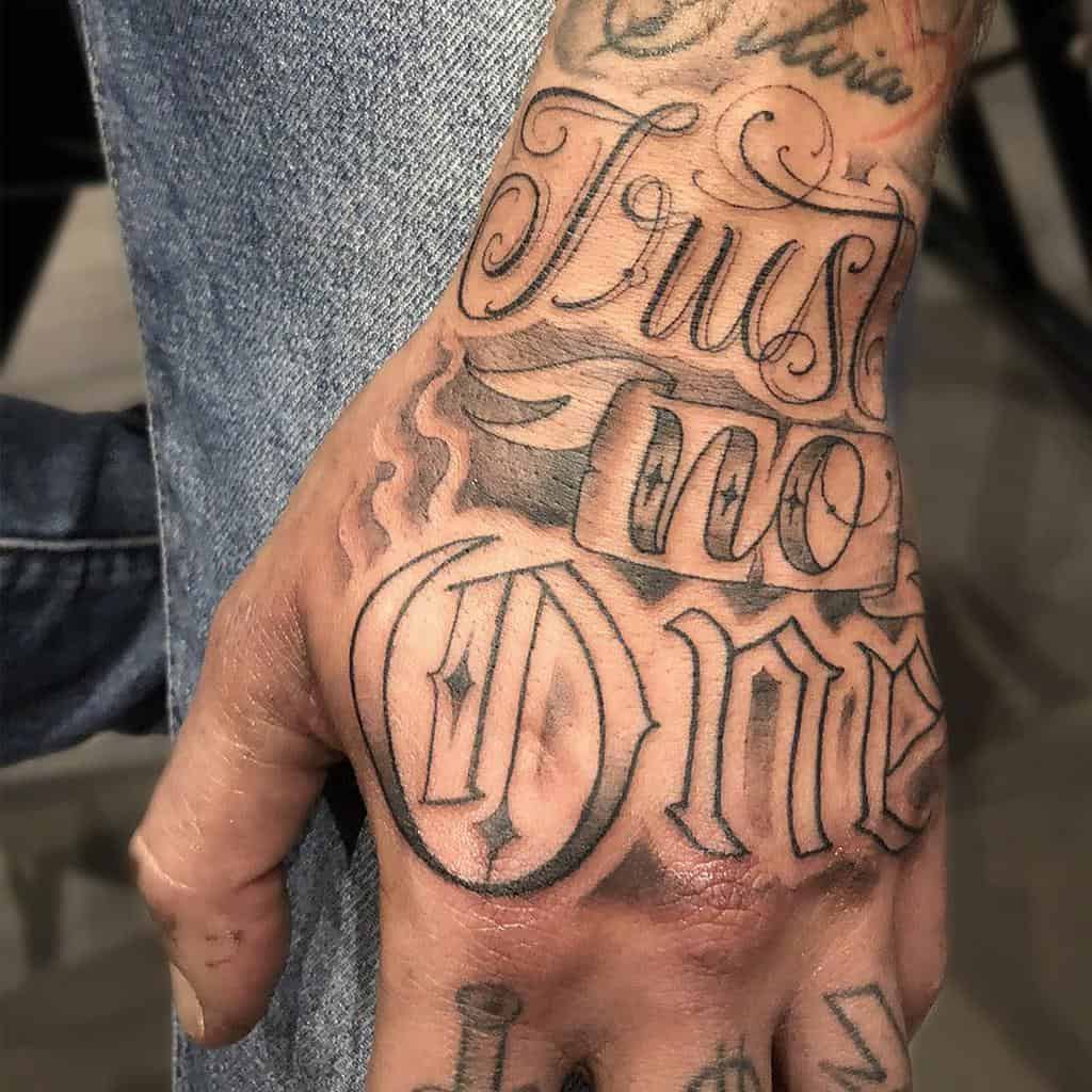 A hand with tattooed words "Trust No One" in bold, ornate lettering