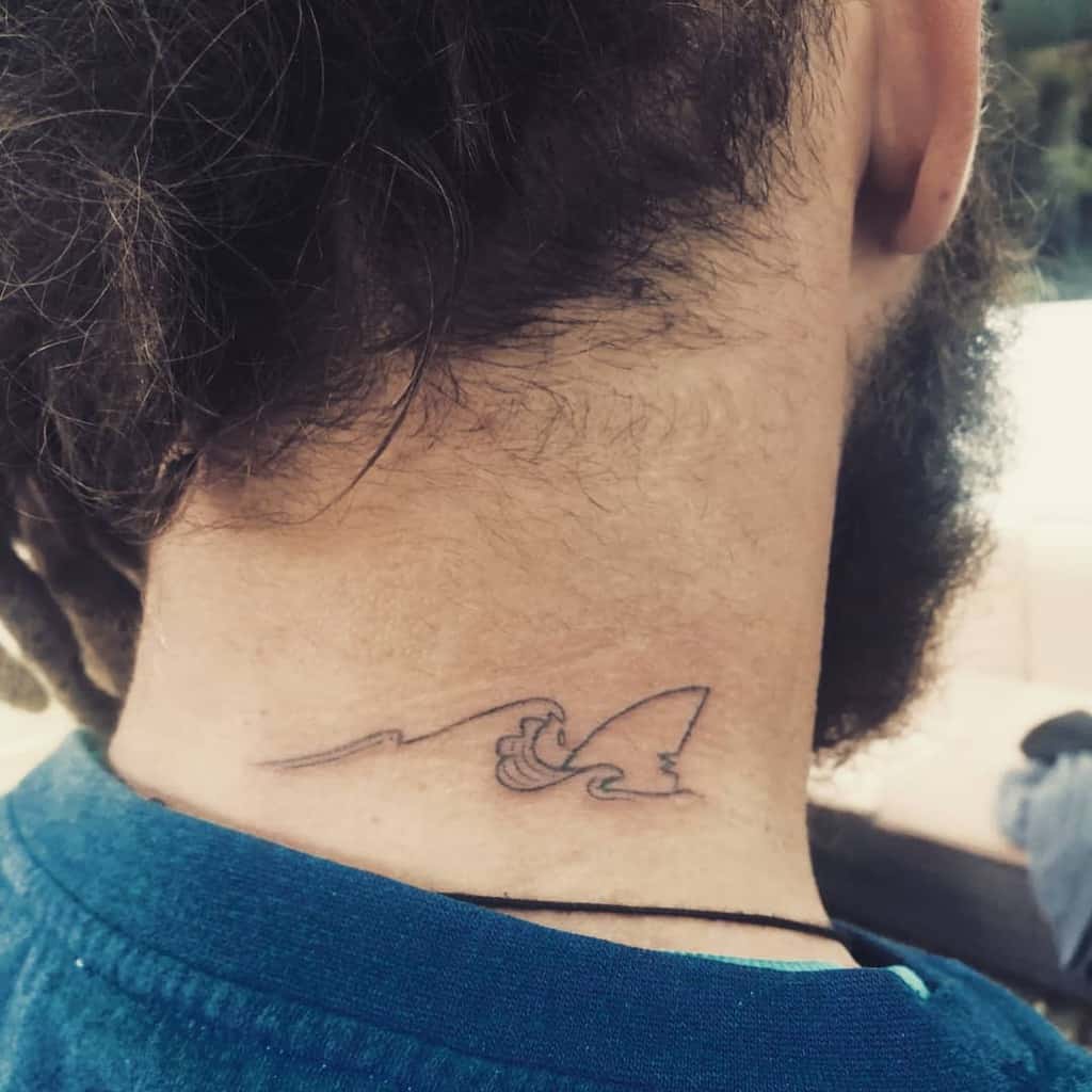 Minimalist shark fin and ocean wave tattoo, featuring fine linework in a simple, elegant design
