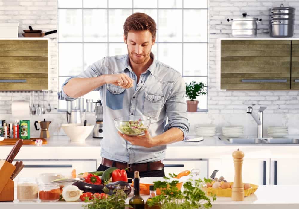 handsome man preparing salad in home