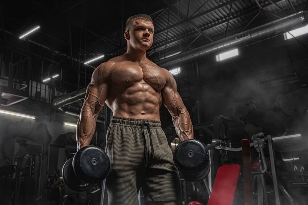 handsome sporty man with naked muscular torso doing weight lifting