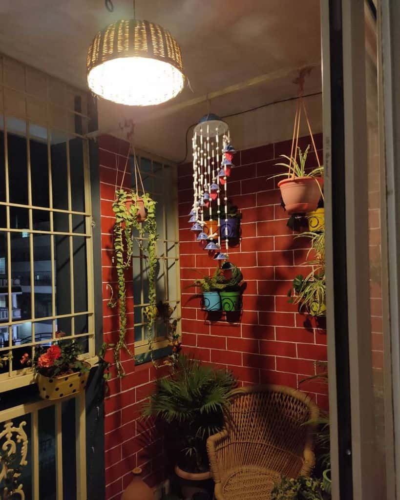 Cozy balcony garden with hanging planters, wicker chair, and decorative lighting.