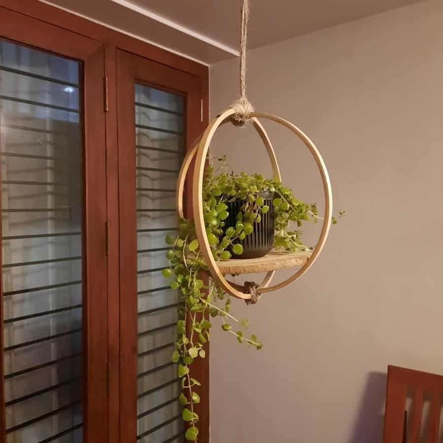 Hanging circular wooden planter with a trailing potted plant, creating a modern indoor decor.