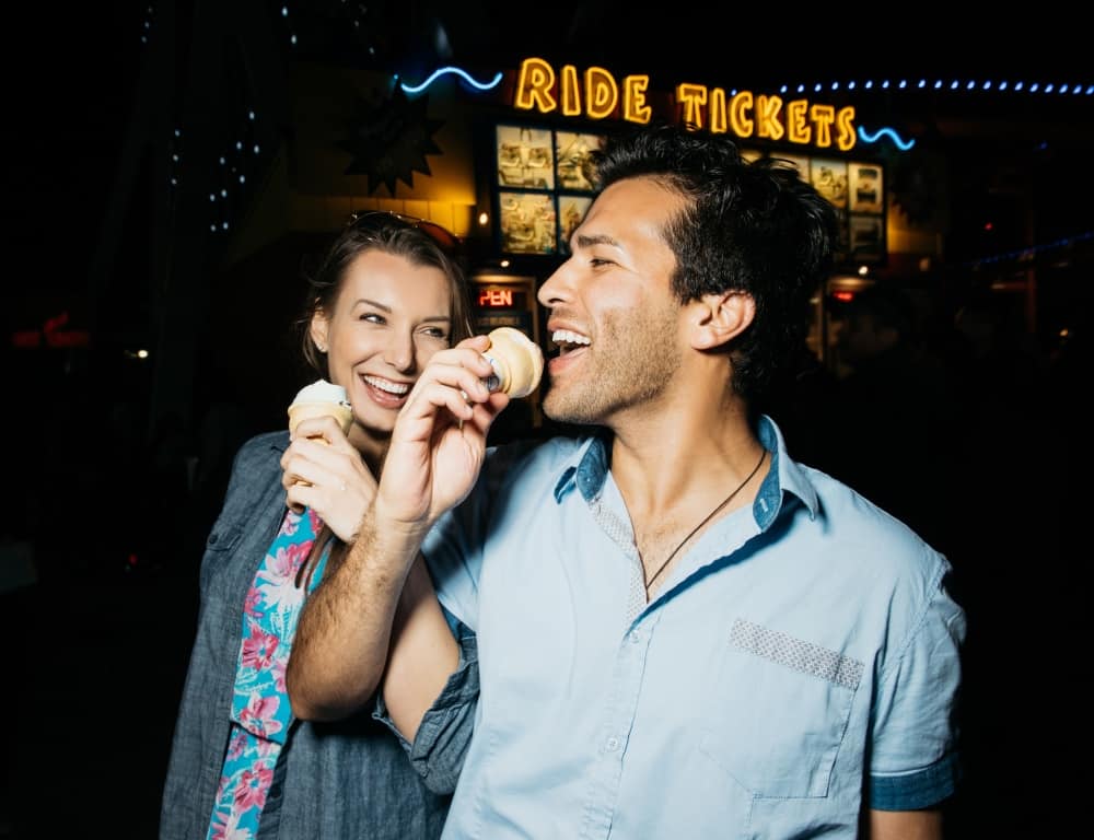 happy couple eating ice cream at the amusement park