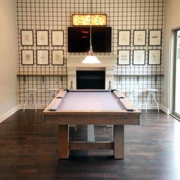 Farmhouse billiard room with plaid accent wall, wooden pool table, and a cozy fireplace.