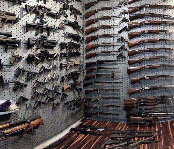 Gun room with pegboard walls displaying rifles and firearms, and hardwood flooring.