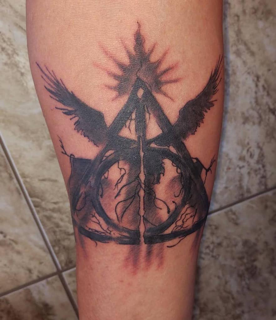 Dark and intricate Deathly Hallows tattoo, featuring a fusion of the iconic symbol with wings, roots, and radiant energy
