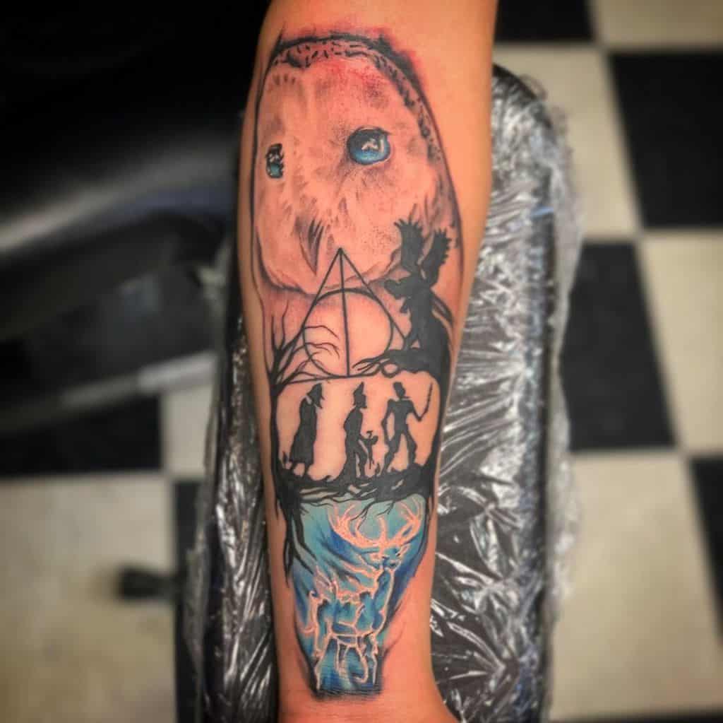 Detailed Deathly Hallows tattoo featuring Hedwig, the Tale of the Three Brothers, Dementors, and a glowing stag Patronus in blue hues.
